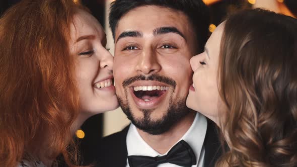 Happy Multicultural Friends Kiss a Surprised Man on New Year Party