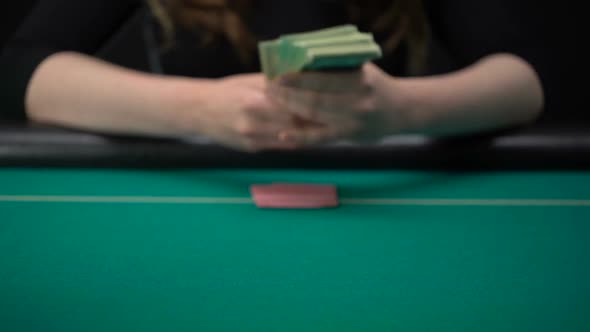 Woman Looking at Cards and Putting Dollars on Casino Table, Wasting Money