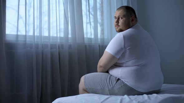 Sad Heavy Man Sitting on Bed at Home, Health Problem, Depression, Insecurities