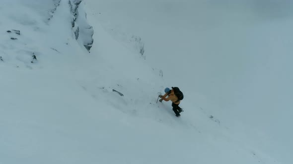 Mountain Climber Using a Pick to Climb a Steep Mountain in the Snow