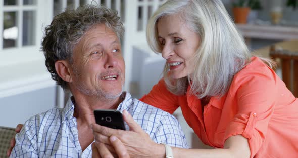 Senior couple using mobile phone on the porch