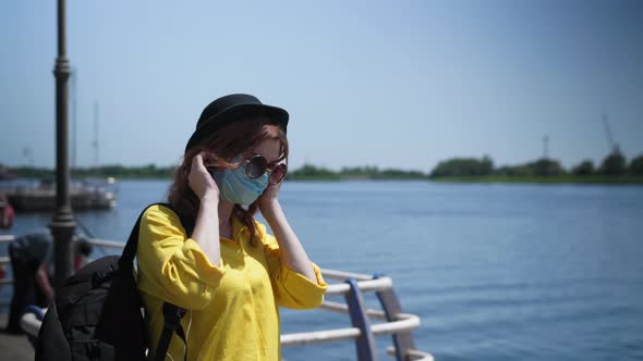 Woman Walks Along Promenade During Pandemic and Self-isolation and Wears Protective Mask Against