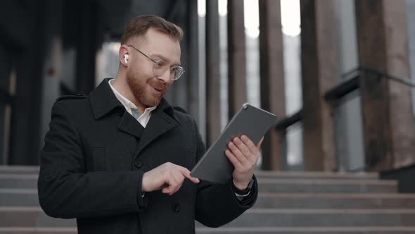 Businessman Looking at the Tablet Screen and Rejoicing at Good News