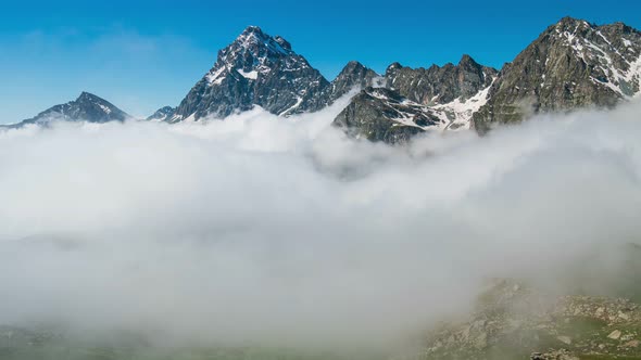 Time lapse, moving clouds in the valley below mountain ridges and peaks of the Alps