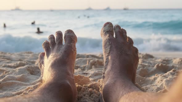 POV Feet of Young Man Lying on Sandy Beach By the Ocean During Sunset Zanzibar