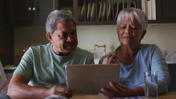 Senior mixed race couple having online medical consultation using tablet