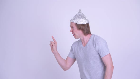 Stressed Young Man with Tinfoil Hat Touching Something and Looking Scared