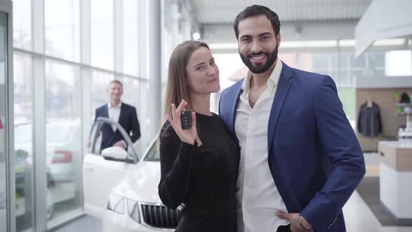 Young Wealthy Multiracial Family Posing in Car Dealership with Keys From New Automobile. Pretty