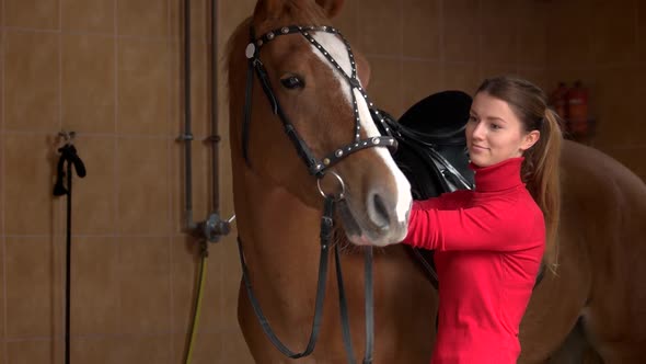 Young Woman Adjusting Horse Bridle at Stable