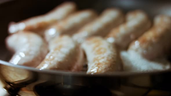 Closeup of Cooking Sausages in Black Pan with Oil