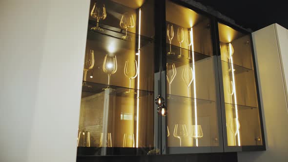 Black Cupboard with Glass Wall in the Kitchen with Crockery and Clear Glasses with Lighting