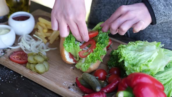 Making Hotdog  Woman Adding Sliced Tomatoes to Bun