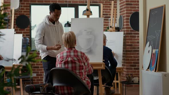 Male Teacher Giving Advice to Elder Woman in Drawing Class