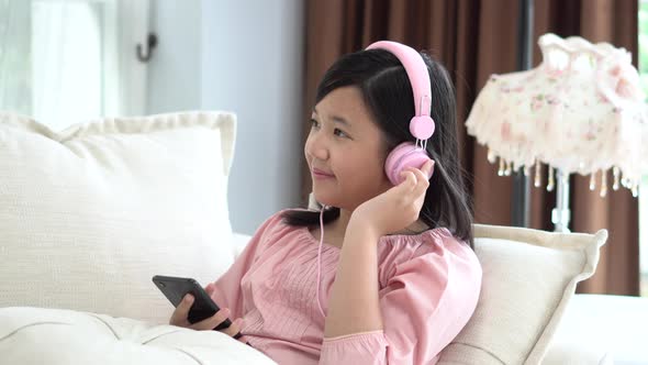 Beautiful Asian Girl Listening To Music  Sitting On A Sofa In The Living Room At Home