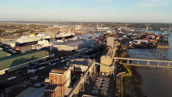 Aerial view flying over port of Tilbury towards two cruise ships moored in Tilbury docks at sunset