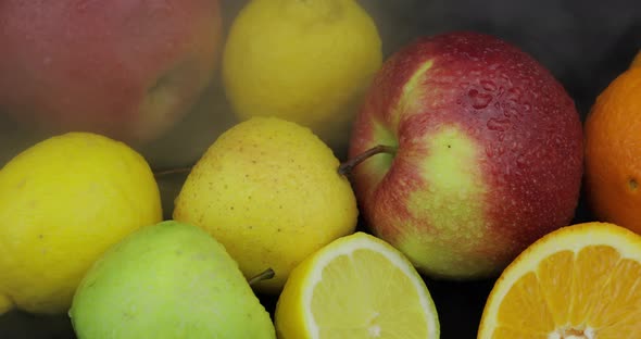 Tropical Lemon, Orange, Apple in Cold Ice Clouds of Fog Smoke on Dark Background