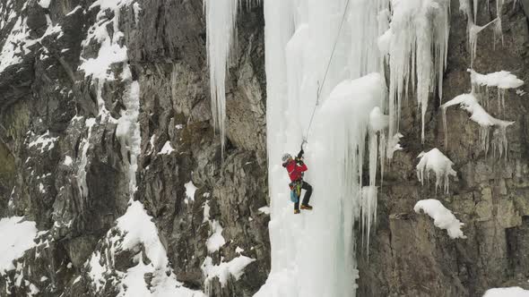 Lone ice climber shakes off ice from axe climbing cascade Maineline, Mount Kineo