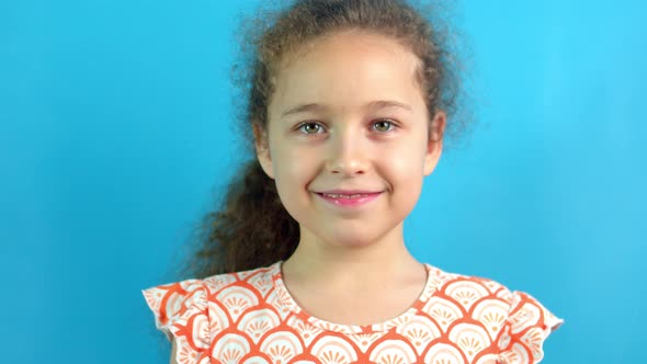 Studio Portrait of a Confident Beautiful Smiling Little Girl Child Laughing Against Blue Background