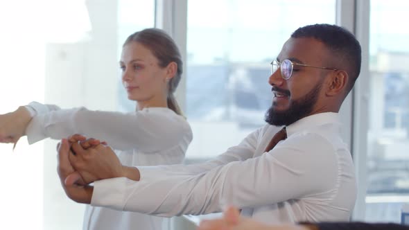 Diverse Office Workers Stretching Arms Together