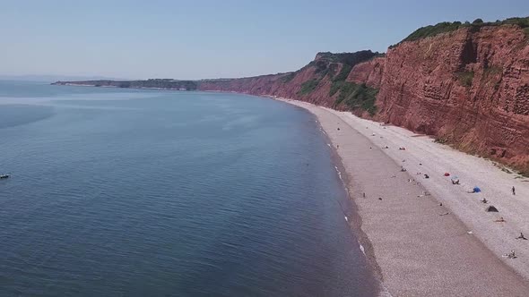 Aerial, flying over the ocean alongside red cliffs in Budleigh Salterton, Jurassic Coast, STATIC CRO