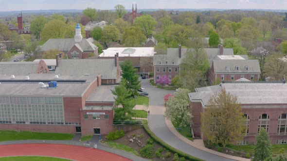 Aerial of college university campus and sports gymnasium beside athletic track. Drone view of trees