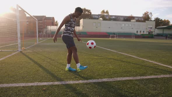 An Active Young Black Girl Training in the Stadium and Juggles a Soccer Ball Against the Background