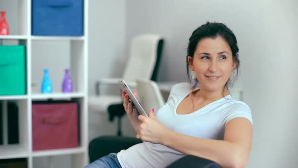 Beautiful Woman Using Tablet Sitting on Sofa at Home