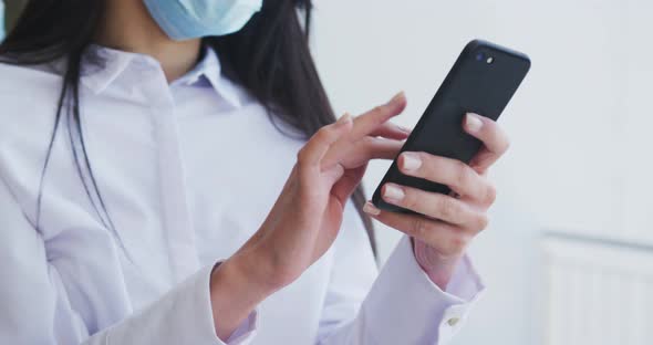 Woman wearing face mask using smartphone