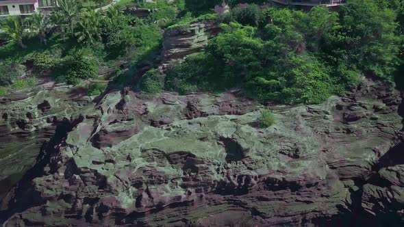 Aerial view of rocky cliffs and crashing waves revealing luxury homes