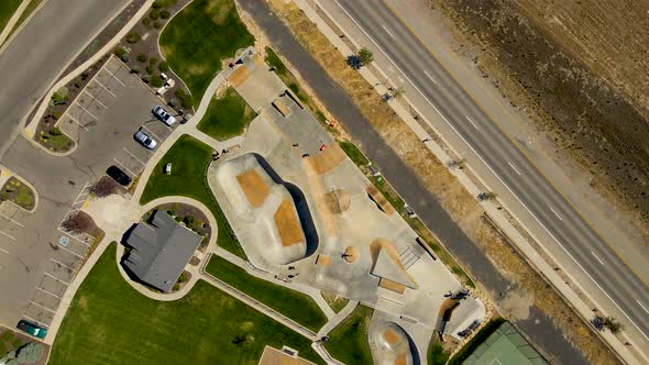 Dizzying aerial spinning view of an urban skate park full of kids having fun in summer