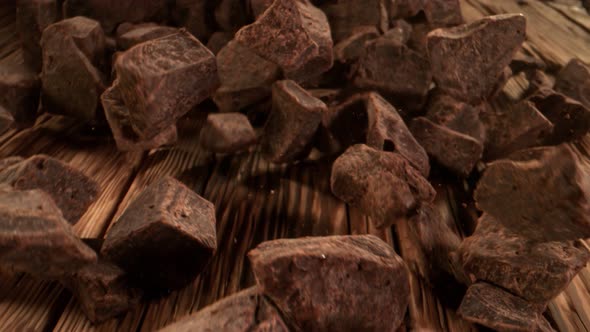 Super Slow Motion Detail Shot of Chocolate Chunks Rolling Towards on Wooden Background at 1000Fps