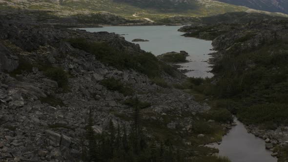 A calm rocky river with mountains encased in fog in the distance in Skagway, Alaska. Filmed from a t