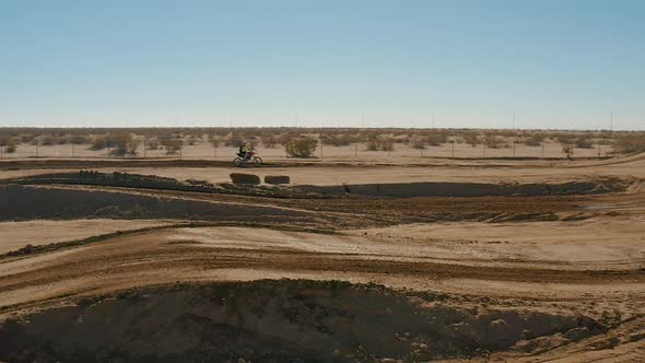 Slow motion aerial view of motocross biker racing on dirt track in Mojave Desert
