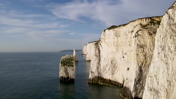 Drone flying between stack and rocky cliff wall of Old Harry Rocks, Dorset. Aerial approach