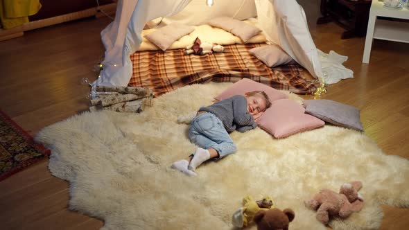 Wide Shot Top View Happy Relaxed Little Girl Smiling Lying on Pillow at Tent in Living Room