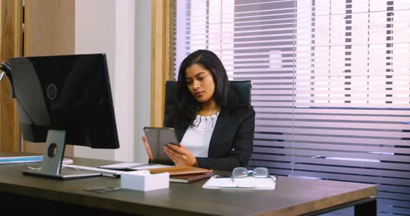 Female executive using digital tablet at desk 4k