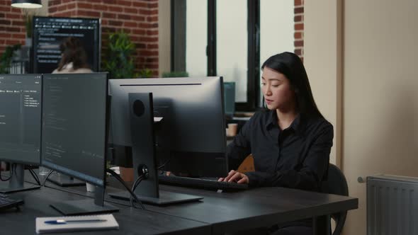 Portrait of Asian Programer Focused on Writing Code Sitting at Desk