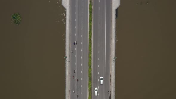 Top down view of modern bridge across a river. Cars, Trucks and motorscooter traffic passes across t