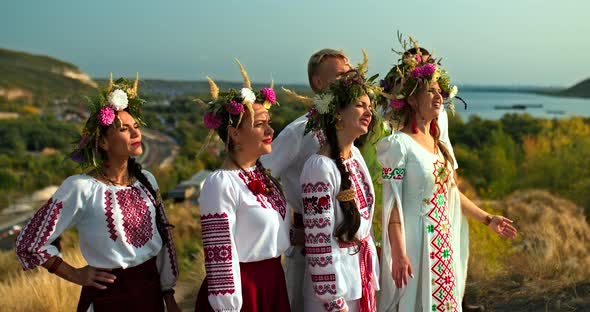 Women in Folk Costumes and with Flower Wreaths on Their Heads are Standing on the Mountain and