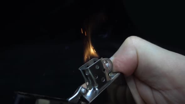 Cigarette Lighter Is Ignited By The Hand On Black Background. Slow Mo 2