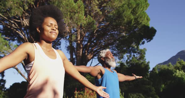 Happy african american senior couple exercising stretching in sunny garden