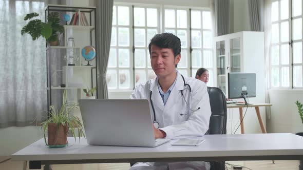 Asian Male Doctor Communicates With Patient By Video Link, Doctor Consults Patient