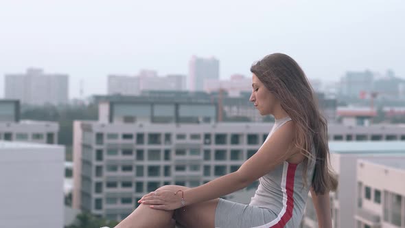 Lady in Knitwear Dress Sits on Roof Against Beautiful View