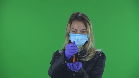 Portrait of Beautiful Young Woman in Medical Protective Face Mask Pours Medicine From Hand To Hand