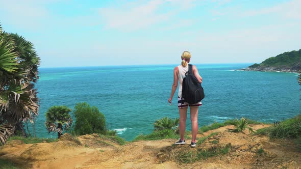 traveler girl with a backpack looking at an island in a tropical lagoon