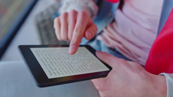 Caucasian Man Touching and Reading Book on His Modern Ereader While Sitting on an Armchair