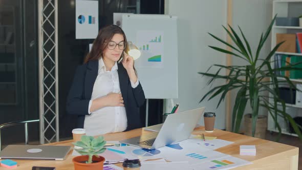 A Beautiful Pregnant Woman Talking on a Cell Phone Sitting at a Table