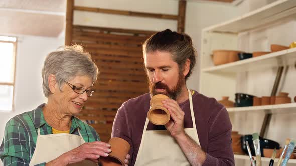 Male and female potter interacting while examining a pot