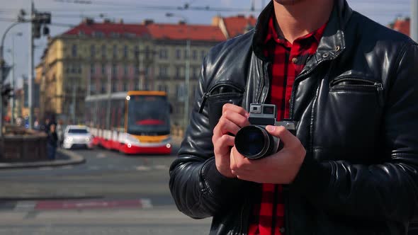 A Man Holds a Camera Against His Chest in a Street - Closeup