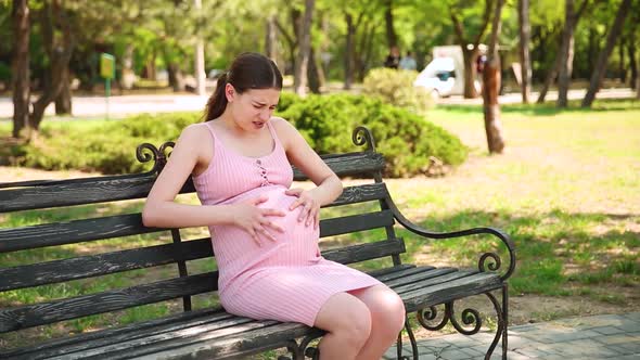 a Pregnant Girl Sits on a Park Bench and Her Stomach Begins to Hurt